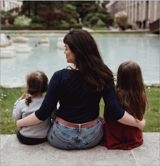 Une mère assise avec ses deux filles sur le bord d'un mur